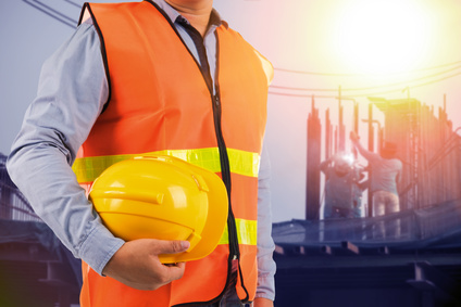 Trabajador con chaleco reflectante sosteniendo un casco de seguridad