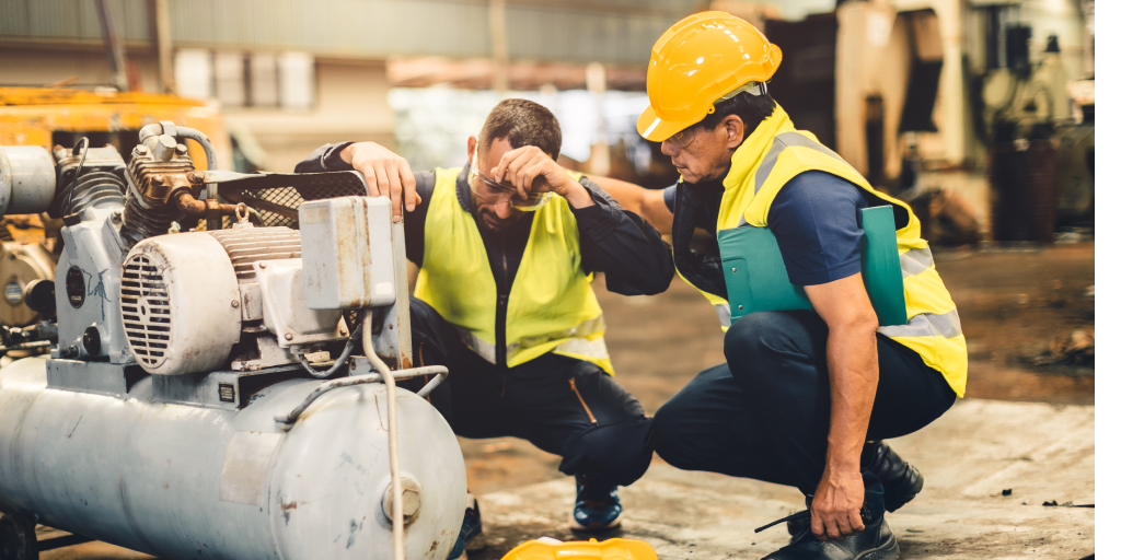 Trabajadores con casco y chaleco reflectante revisando equipo industrial